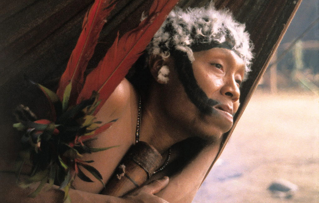 A Yanomami warrior from a "friendly village" rests in a hammock while visiting his neighbors.