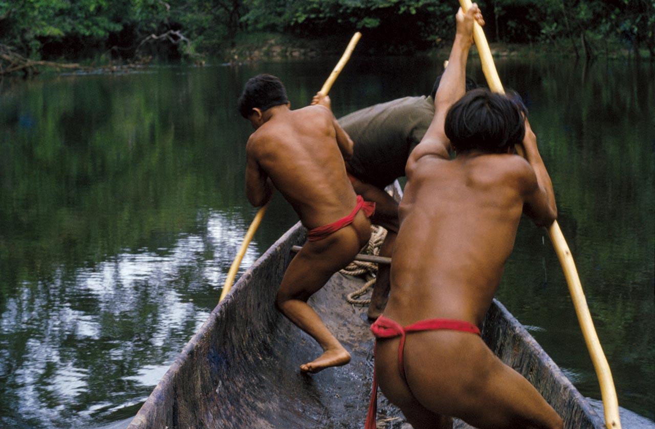 Sanemá Indians learning how to handle a curiara (canoe) built by the Ye´kwana, while traveling in shallow waters of the Cuchime River, Venezuela.